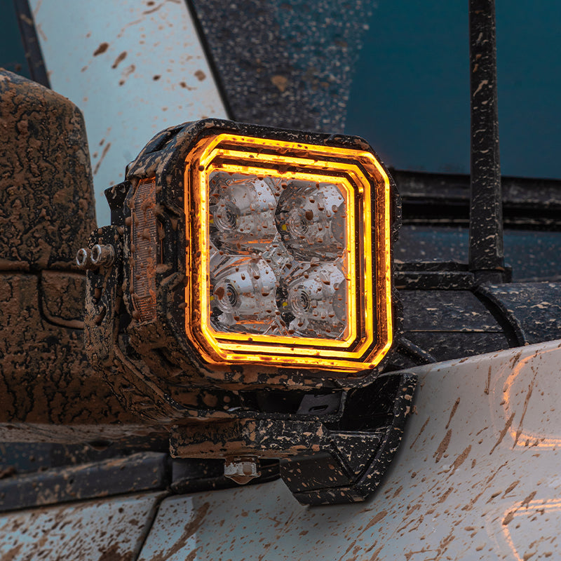 SUPAREE HYPER Series 5-inch LED Pod Lights with Stepped Halo, DRL, IP69K Waterproof installed on Jeep Wrangler JL â€“ Close-up of muddy LED pod with amber halo DRL.